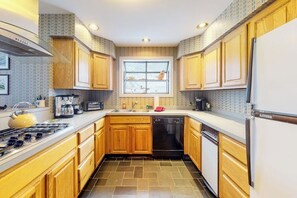 A compact kitchen with wooden cabinets, a gas stove, a dishwasher, and a window with a view of the outside. - Light-filled, dog-friendly home with fireplace & great location near skiing/golf (Avon)