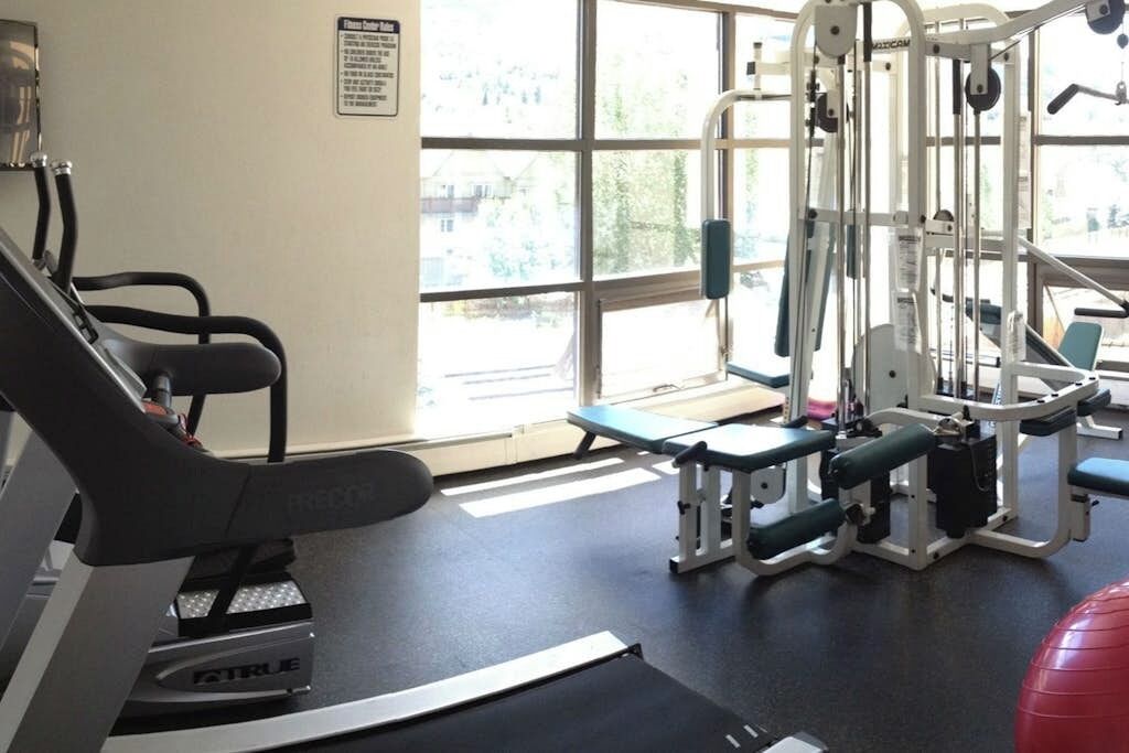 Ett gym med konditionsmaskiner, styrketräningsmaskiner och en röd träningsboll.