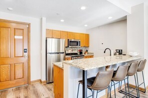 Eine moderne Küche mit Holzausstattung, Edelstahlgeräten und einer Bar mit Sitzgelegenheiten.