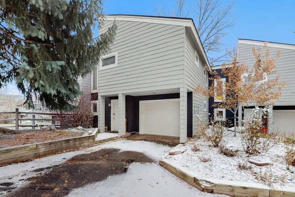 Ein zweistöckiges Wohnhaus mit Garage und überdachter Auffahrt, inmitten einer verschneiten Landschaft.