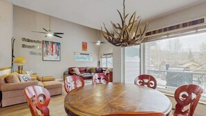 Zona pranzo con tavolo rotondo e sedie, una ventola a soffitto e un'ampia finestra con vista.