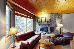 Ein gemütliches Wohnzimmer mit Kamin aus Stein, Ledermöbeln und Holzboden.