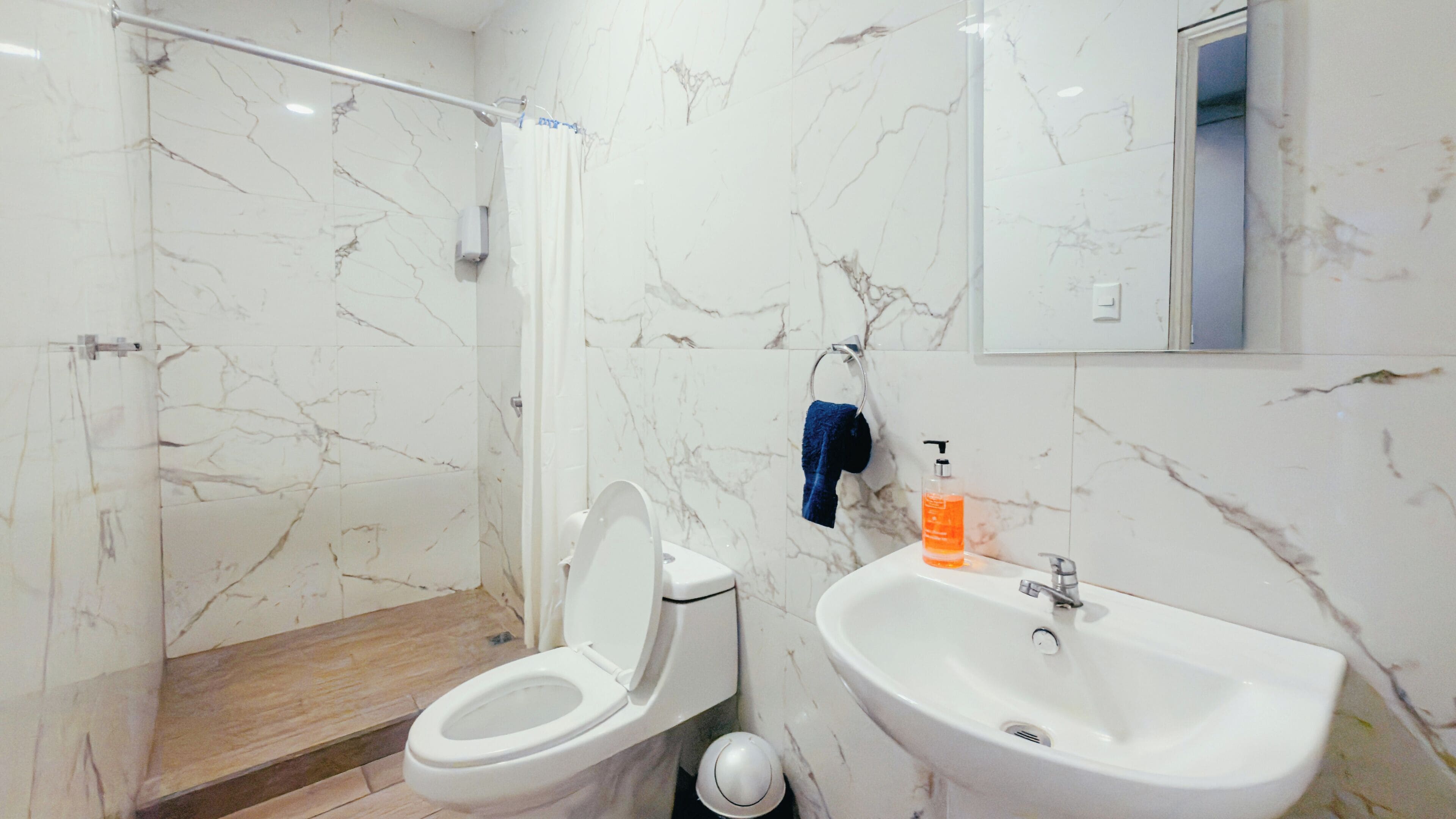 A bathroom with a toilet, sink, and shower.