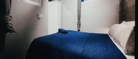 A bedroom with a bed, a window, and a door.