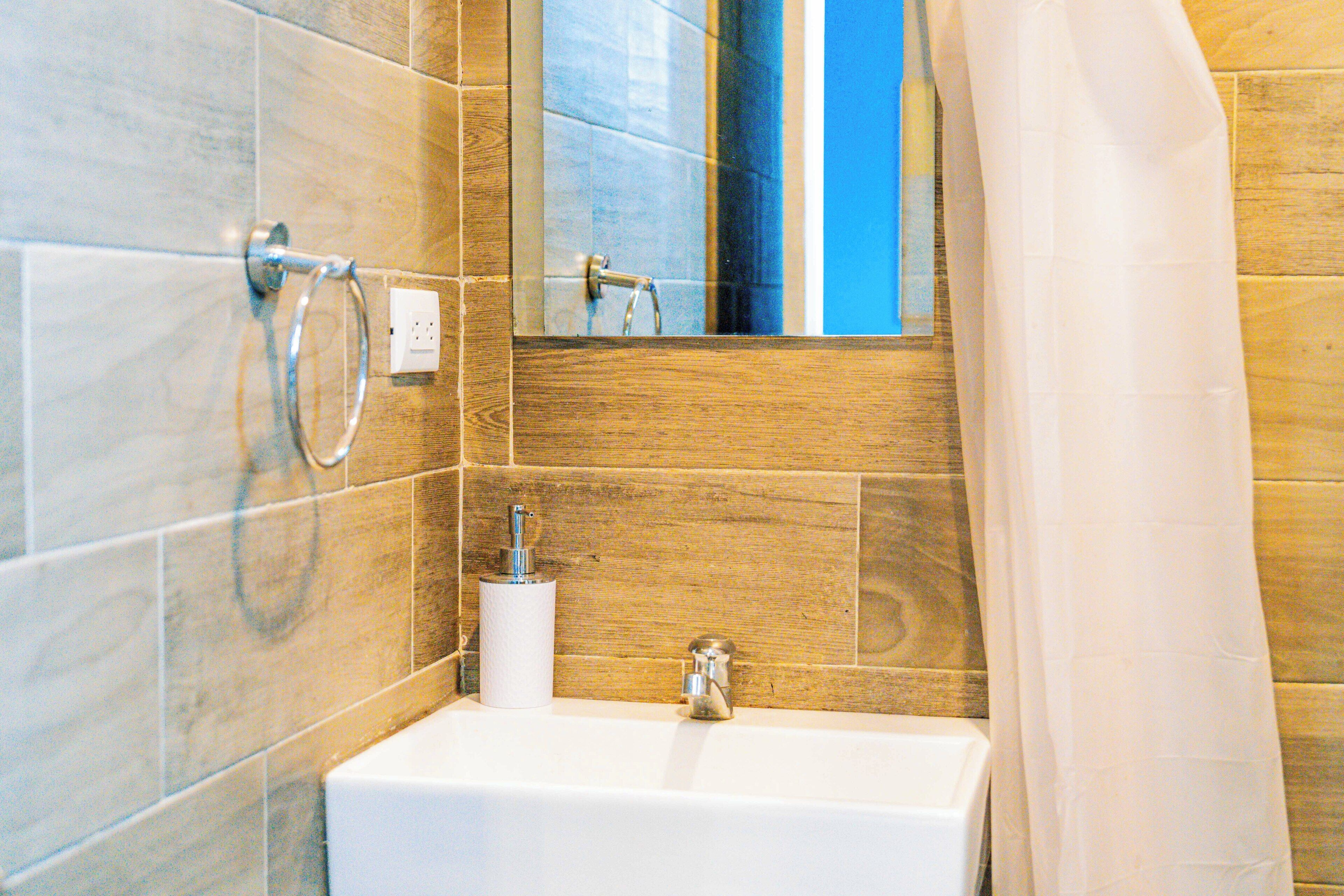 A bathroom with a white sink, a mirror, a towel rack, and a shower curtain.