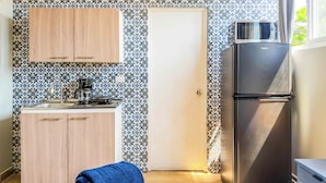 A compact kitchen with a coffee maker, a refrigerator, and patterned tile walls. - Villa Verona (Guatemala City)