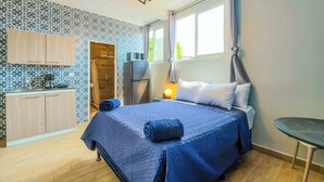 A bedroom with a bed, a nightstand, a table, a microwave, a wardrobe, and a shower. - Villa Verona (Guatemala City)