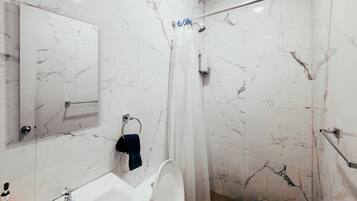 Une salle de bain équipée d’une douche, de toilettes, d’un lavabo et d’un miroir.