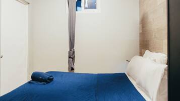 A room with a bed, a window with a curtain, and a door.
