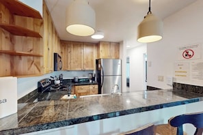 Eine moderne Küche mit Holzschränken, Edelstahlgeräten und einer Arbeitsplatte aus Granit.