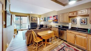 A compact living space with a dining area, kitchenette, and a large window providing natural light. - Mountain getaway near trails & skiing w/ balcony &  shared amenities (Avon)