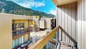 A multi-story building with balconies, a wooden deck, and a mountainous backdrop. - Mountain getaway near trails & skiing w/ balcony &  shared amenities (Avon)