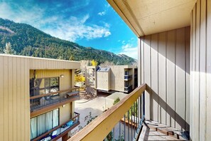 Ein mehrstöckiges Gebäude mit Balkonen, einer Holzterrasse und einer Bergkulisse.