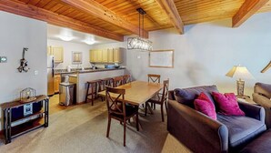 Tilava olohuone, jossa on puinen katto, ruokapöytä ja sohva.