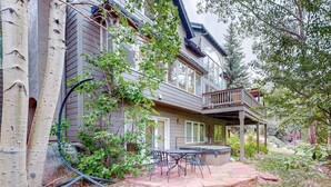 Ein zweistöckiges Haus mit überdachter Terrasse, Gartenmöbeln und einem Garten.