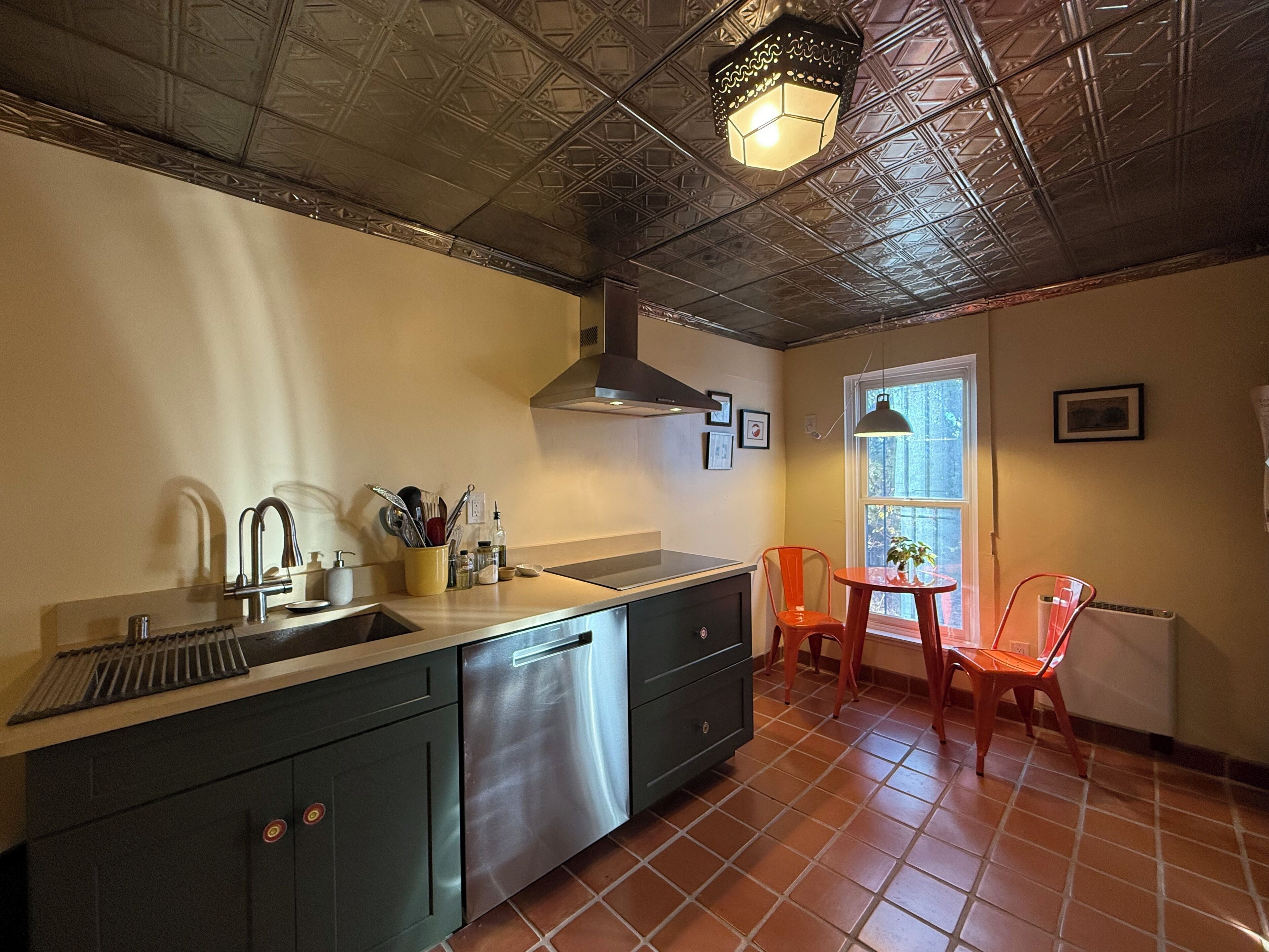 A kitchen with a stainless steel sink, a range hood, and a window with a view.