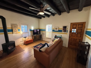 A living room with a sofa, a television, a fireplace, and a ceiling fan. - Railyard Rose: explore Santa Fe on foot from this central oasis (Santa Fe)