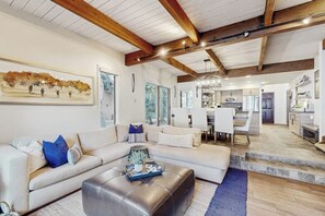 Ein modernes Wohnzimmer mit Ecksofa, Couchtisch und Essbereich mit einer Chandelier.