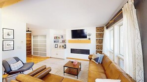 A living room with a sofa, a coffee table, and a TV mounted on the wall. - Cozy, recently remodeled condo with patio, mountain views & W/D - near slopes (Avon)