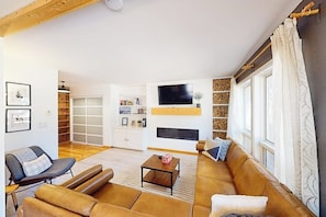Ein Wohnzimmer mit einer Couch, einem Couchtisch und einem an der Wand befestigten Fernseher.