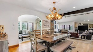 Un vaste espace dédié à la salle à manger, avec une grande table en bois, des bancs et un lustre original.