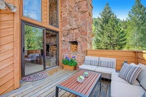 Eine Holzterrasse mit einer Steinmauer, einer Couch und einem Tisch mit Dekoration.
