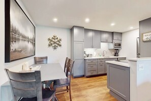 A modern kitchen with grey cabinets, a microwave, and a coffee maker. - Lovely condo with fireplace, mountain view, full kitchen, & skiing nearby (Avon)