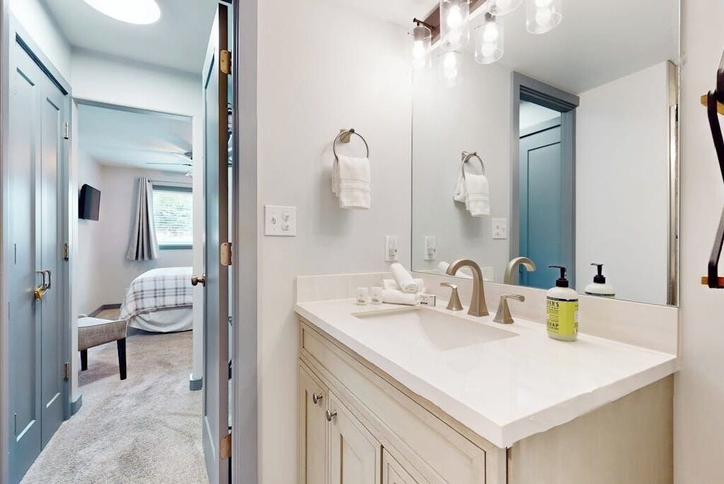 A modern bathroom with a large mirror, a sink, and a shower.