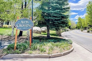 Ein Straßenschild für Avon Crossing zeigt eine Straße, die sich nach rechts windet, umgeben von Grünflächen und Bäumen.