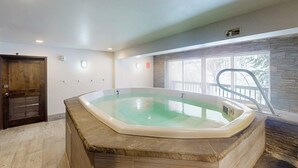 A hot tub in a room with a wooden door, a window with a view, and a ceiling light. - Cozy condo with amazing mountain view, pool & hot tub - next to golf/Nordic ski (Vail)