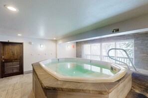 A hot tub in a room with a wooden door, a window with a view, and a ceiling light. - Cozy condo with amazing mountain view, pool & hot tub - next to golf/Nordic ski (Vail)