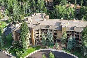 A multi-story hotel with a central courtyard, surrounded by trees and other buildings. - Cozy condo with amazing mountain view, pool & hot tub - next to golf/Nordic ski (Vail)