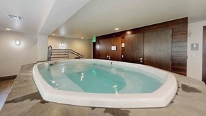 A hot tub in a room with a staircase, wooden paneling, and a tiled floor. - Cozy condo with amazing mountain view, pool & hot tub - next to golf/Nordic ski (Vail)