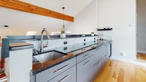 A modern kitchen with a granite countertop, stainless steel appliances, and a wooden ceiling beam. - Townhome with stunning mountain views, fireplace, deck, enclosed patio, & W/D (Avon)