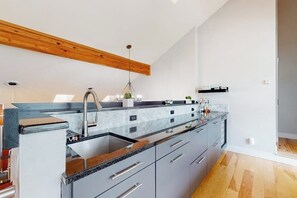 Eine moderne Küche mit Granitarbeitsplatte, Edelstahlgeräten und einem Holzbalken an der Decke.