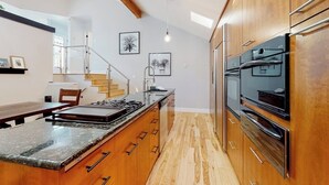 A modern kitchen with wooden cabinets, a granite countertop, and stainless steel appliances. - Townhome with stunning mountain views, fireplace, deck, enclosed patio, & W/D (Avon)