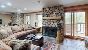 Una sala de estar con chimenea de piedra, un sofá, una mesa de centro y un televisor.