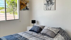Een slaapkamer met een bed, een raam met uitzicht op groen en een airconditioning aan de muur.