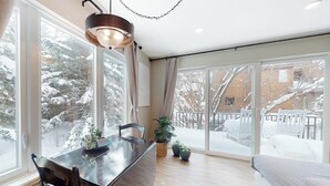 Een modern interieur met een eetgedeelte, grote ramen en uitzicht op een besneeerd landschap.