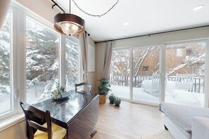 Ein modernes Interieur mit Essbereich, großen Fenstern und Blick auf eine verschneite Landschaft.