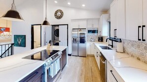 Una cocina moderna con armarios blancos, electrodomésticos de acero inoxidable y una isla central.
