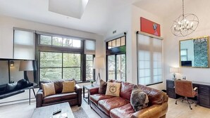 Una sala moderna con un sofá de cuero, una mesa de centro y un televisor.