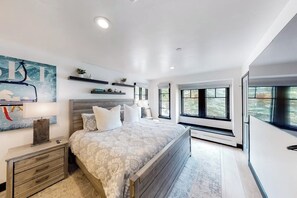 Ein Schlafzimmer mit einem Bett, Nachttischen, einem Wandregal und einem großen Fenster.