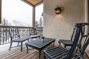 Ein überdachter Außenbereich mit Tisch und Stühlen, einer Topfpflanze und einer wandmontierten Leuchte.