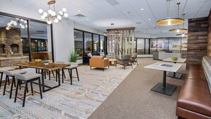 Eine moderne Hotelhalle mit einem Holztisch, Sofas, einem gemusterten Teppich und einer Rezeption.