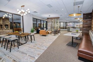 Eine moderne Hotelhalle mit einem Holztisch, Sofas, einem gemusterten Teppich und einer Rezeption.