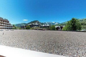 Ein Hotel mit einem Kieshof, mehrstöckigen Gebäuden und einer Bergkulisse.