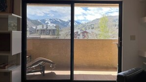 Una habitación con puerta de vidrio corredera que da a un balcón con vistas a la montaña.