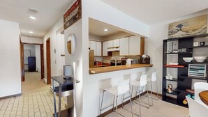 Una cocina moderna con barra, taburetes blancos y una mesa de comedor.