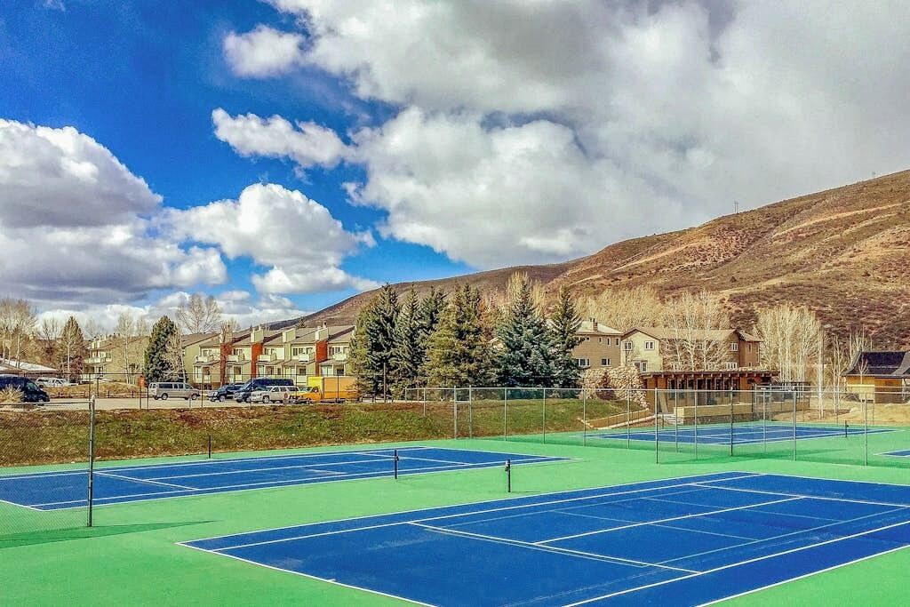 A tennis court with a clear sky and mountains in the background.